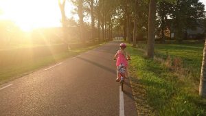 Kleines Mädchen auf Landstraße mit dem Fahrrad