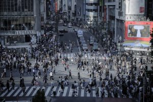 Straßenkreuzung in Tokyo mit vielen Fußgängern, die quer über die Kreuzung laufen
