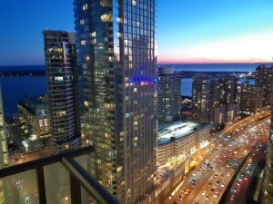 Downtown Toronto mit Hochhäusern, dem Blick auf den Ontariosee bei Sonnenuntergang und einer mehrspurigen Schnellstraße.