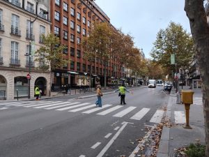 Schülerlotsen auf einem Pariser Boulevard helfen am Zebrastreifen einer Frau beim Überqueren