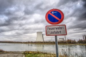 Feuerwehrzufahrt-Zeichen vor einer überfluteten Zufahrt an einem Fluss, vermutlich die Weser, auf der anderen Seite ein Atomkraftwerk.