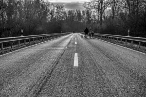 Landstraße mit Leitplanken und Fußgängern auf der Fahrbahn.